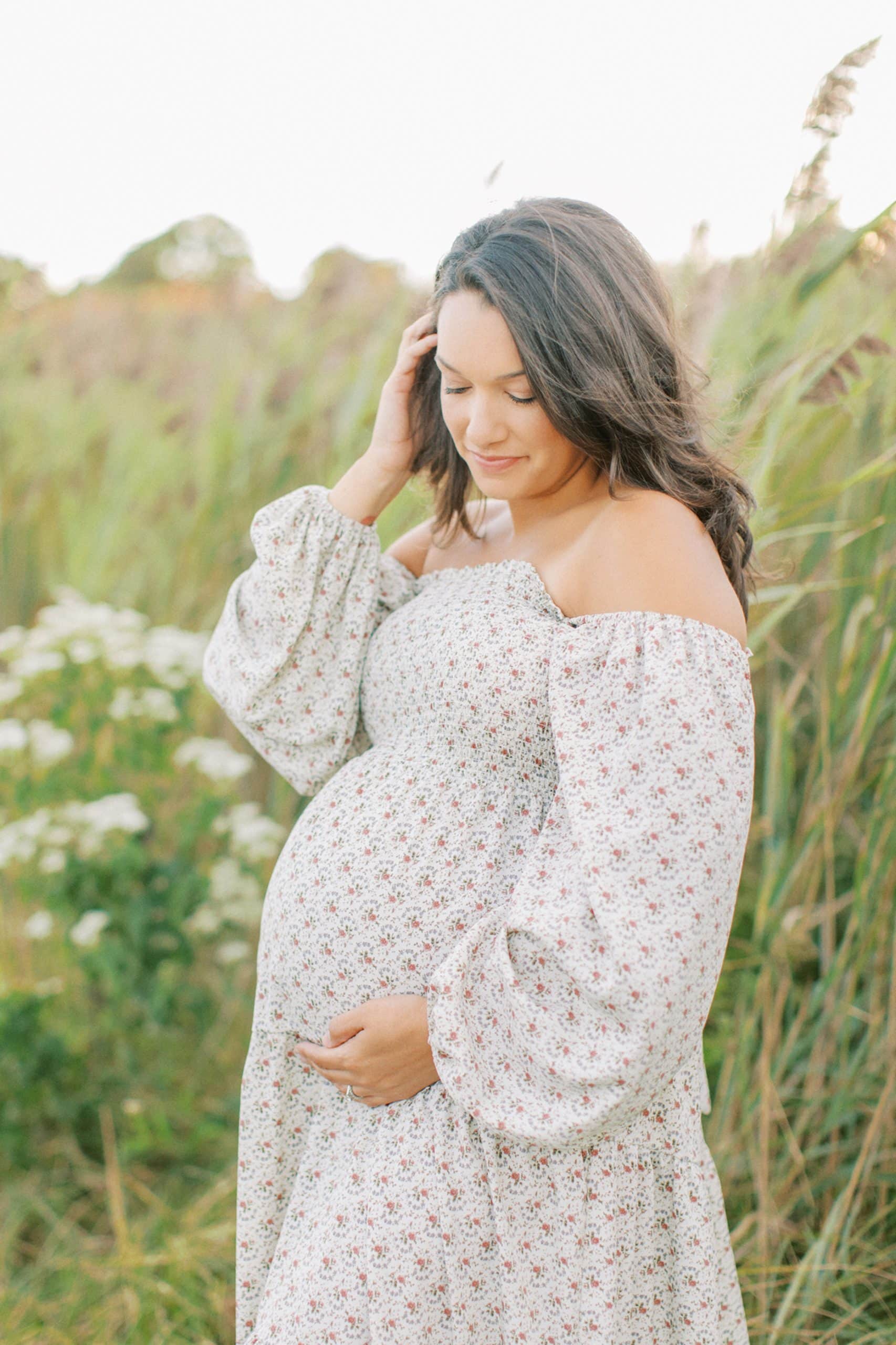 Mother holding back hair while staring down at pregnant belly.