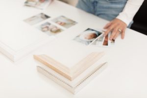 A close up image of hands on a table aligning photos and frame corners.