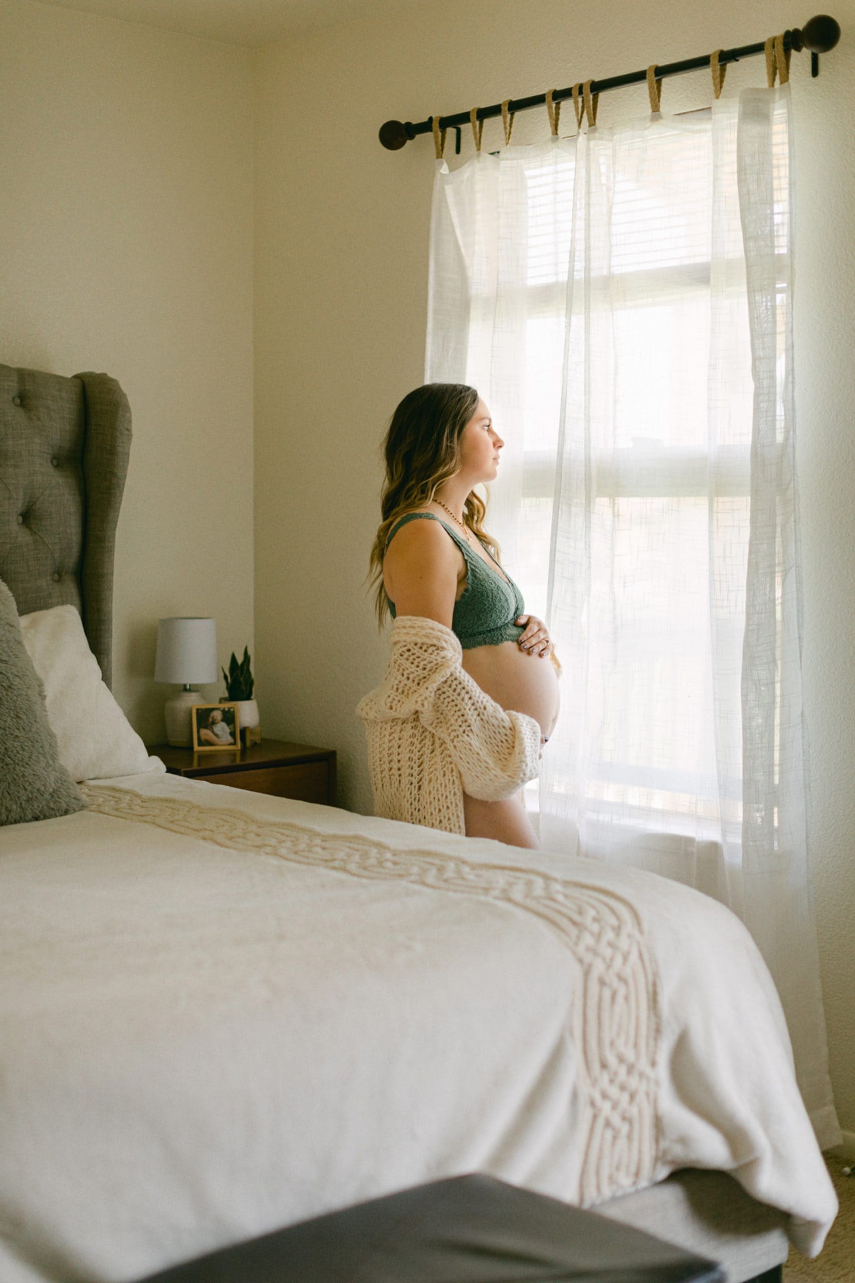 Pregnant women looking out at window during maternity session.