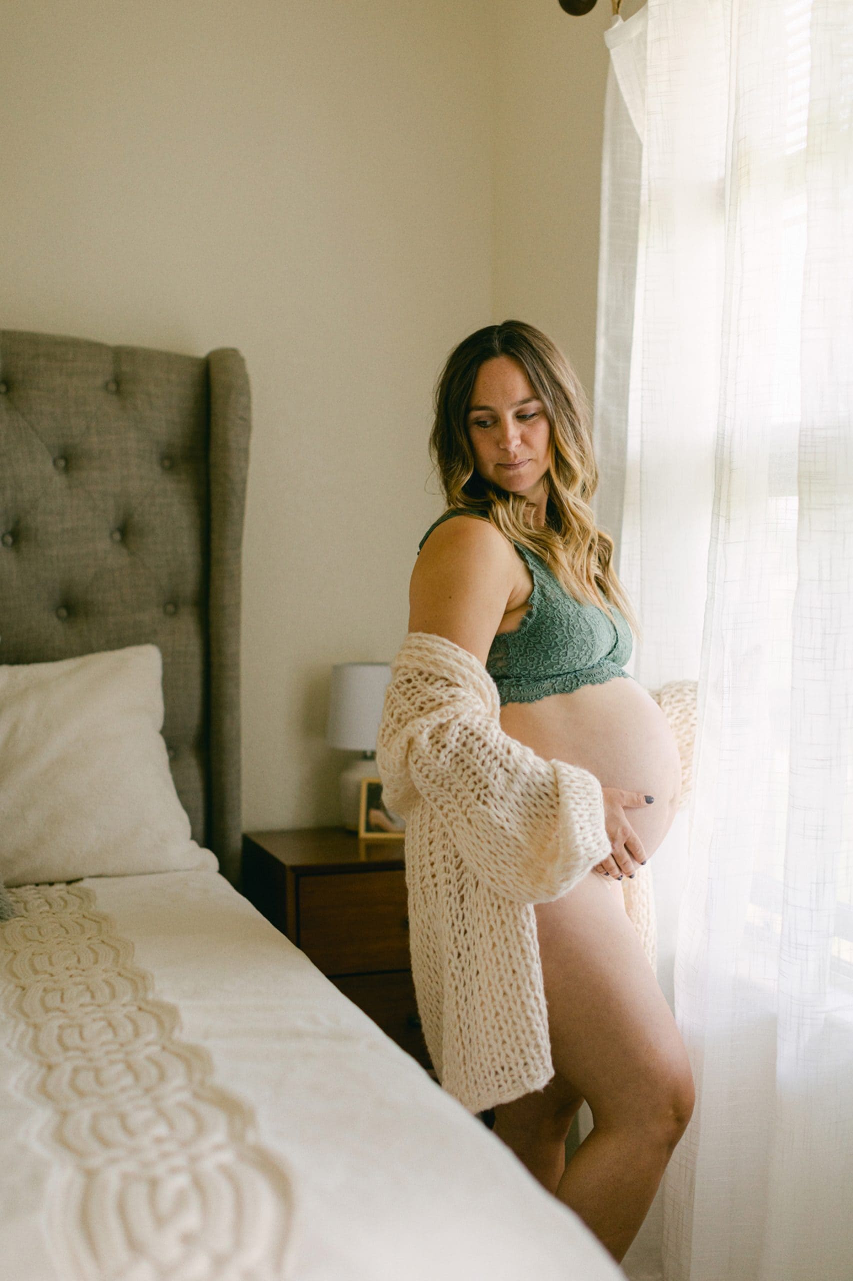 In-home maternity session in Jacksonville, Florida. Women looking back while holding pregnant belly.