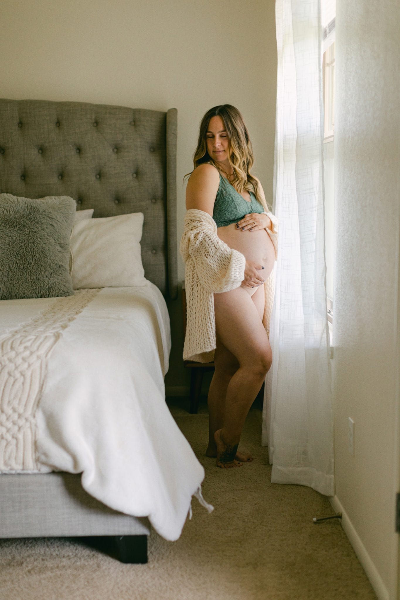 In-home maternity session in St. Augustine, Florida. Women holding belly while posing for portrait.
