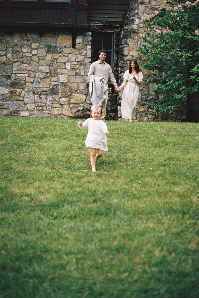 Photo of little girl running away from parents during their outdoor family session.