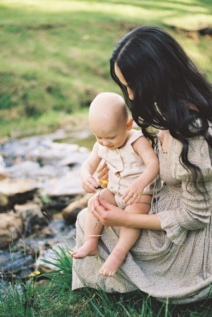 Moher holding son while showing him a flower during family session in Jacksonville, FL.