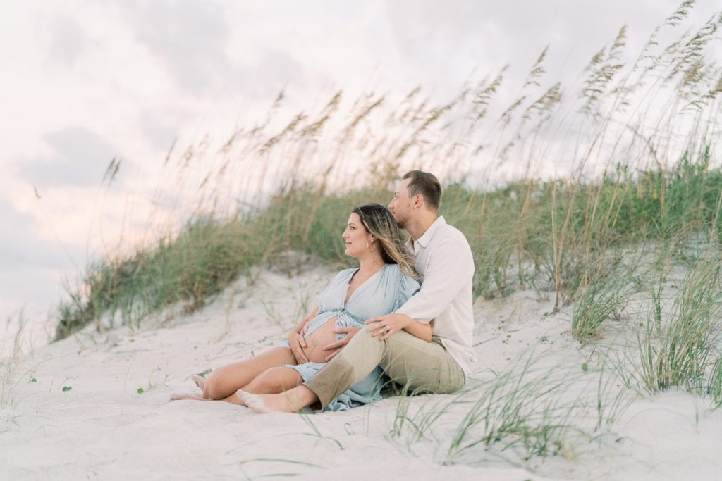 Couple sitting on beach during their jacksonville maternity photography session.