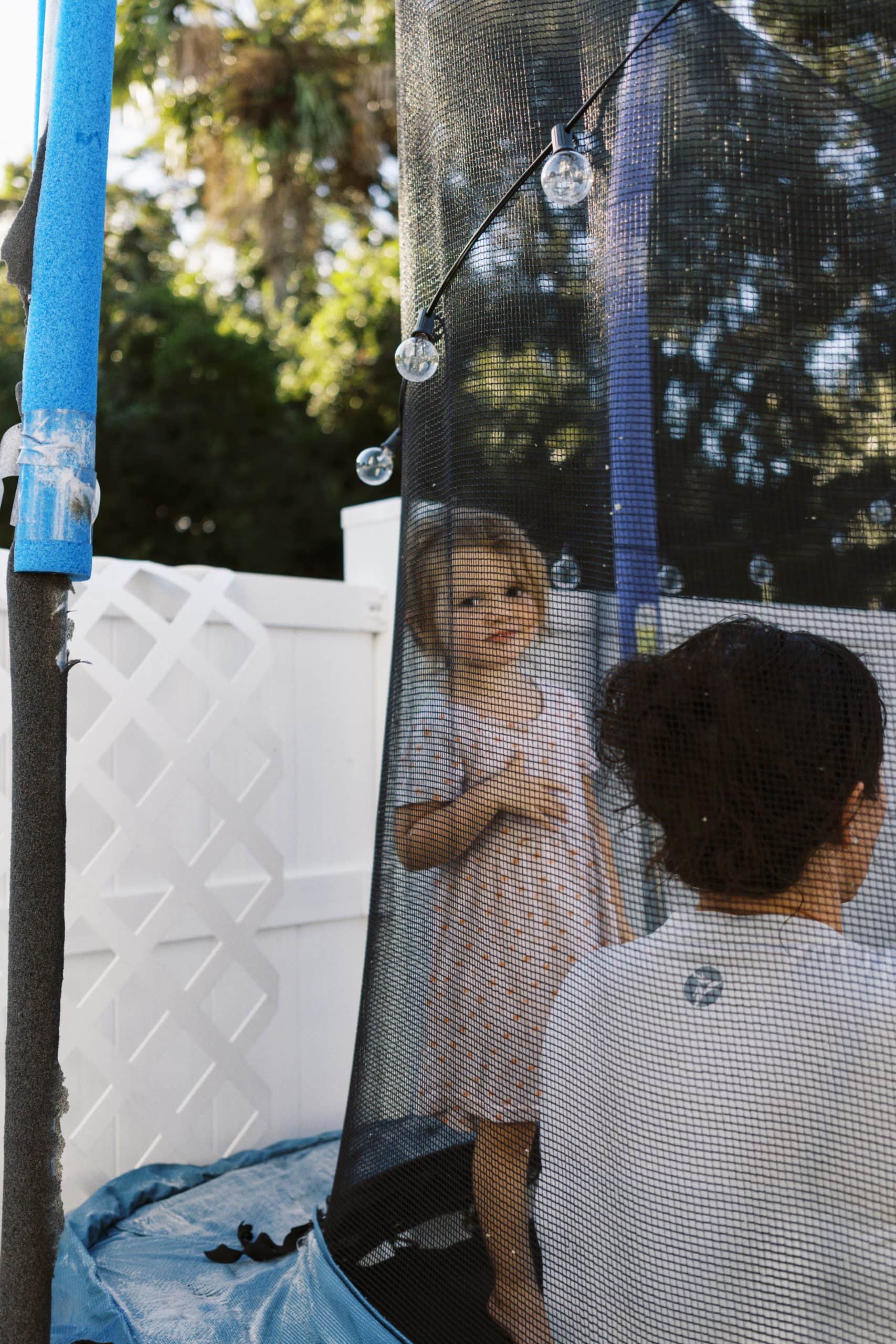 Little girl looking at the photographer while playing on the trampoline.