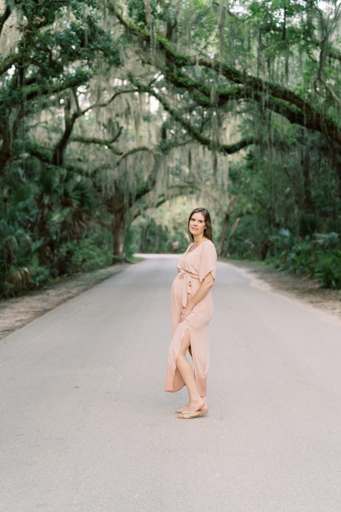 Pregnant mother posing under oak trees during her maternity session in Fernandina Beach, FL.