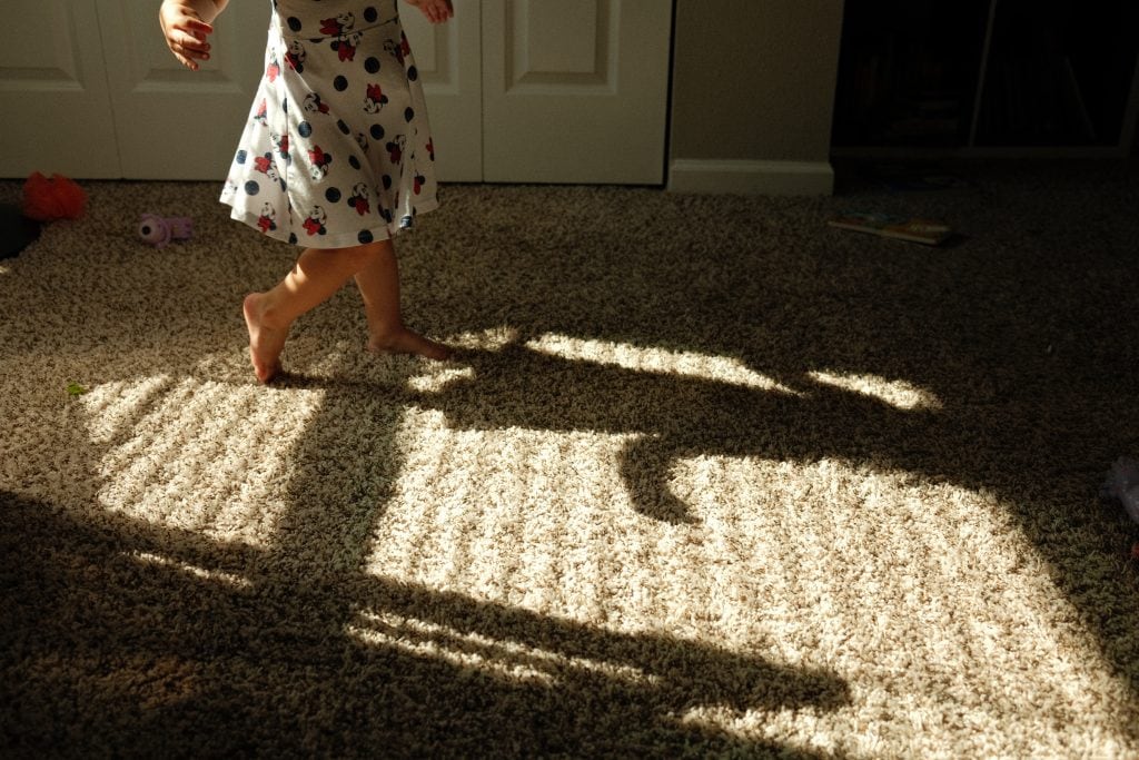 Florida family documentary photographer, picture of little girl dancing in dark room with her shadow on the floor.