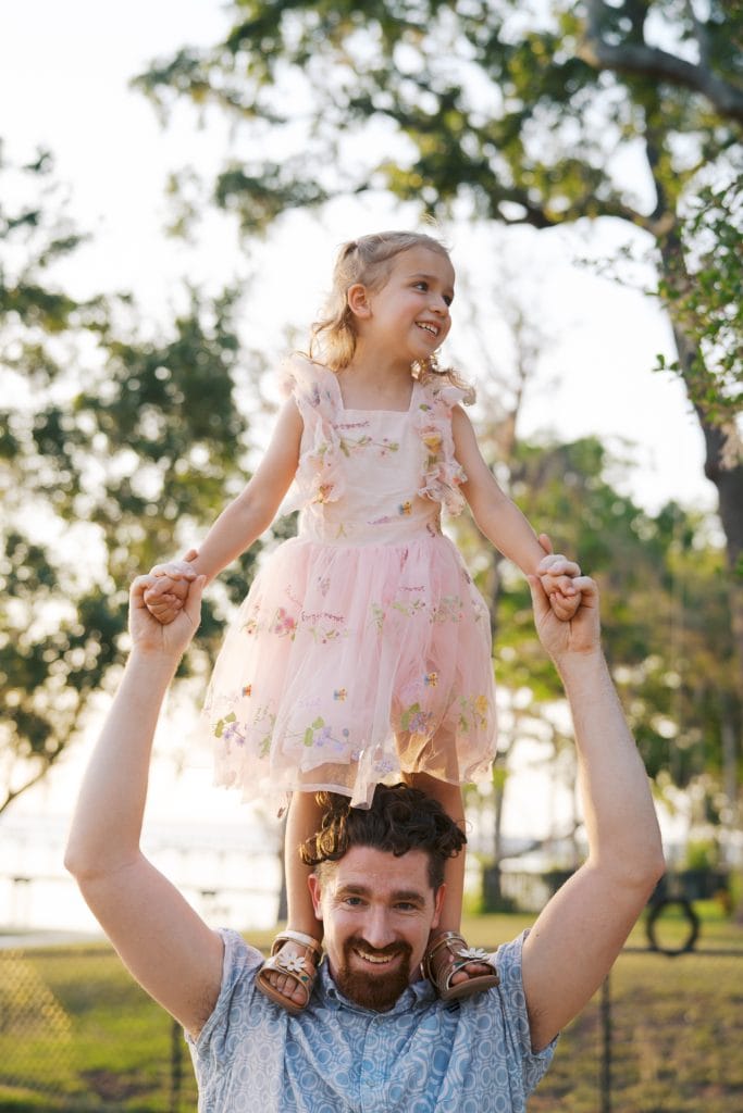 Happy father lifting young girl in a park during daytime.